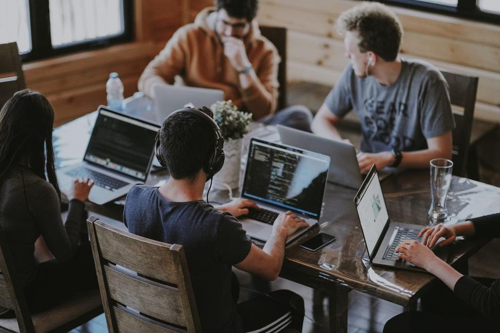 Equipo trabajando con portátiles alrededor de una mesa