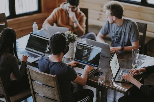 Equipo trabajando con portátiles alrededor de una mesa